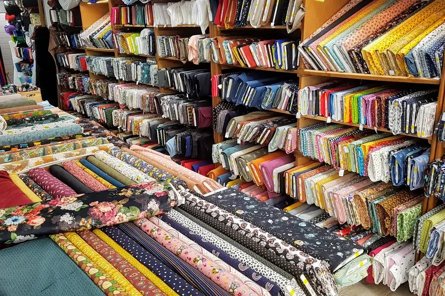 Rayons de tissus pliés par coloris dans la boutique